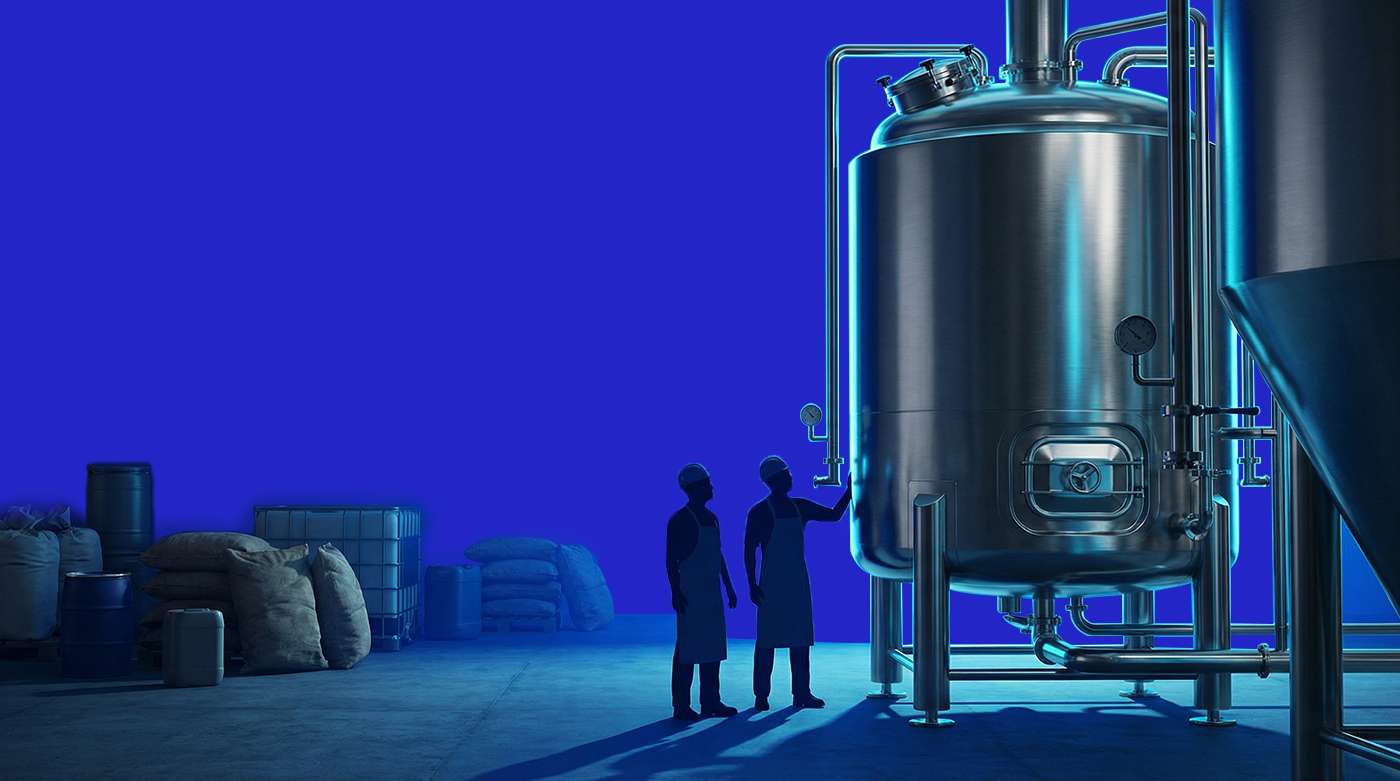 Industrial food production tank with operators inspecting equipment, representing commodity exposure and margin risk in manufacturing
